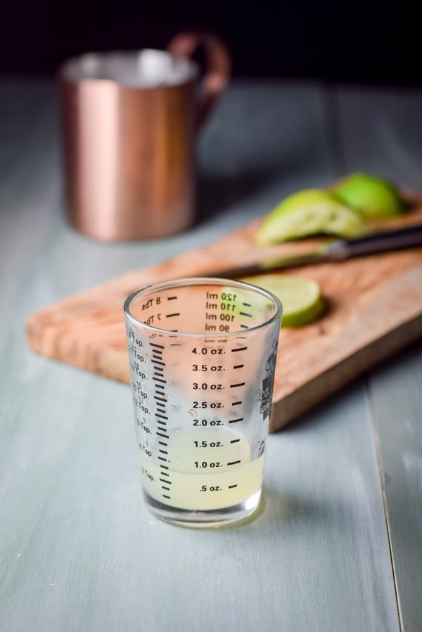 lime juice squeezed and measured with lime in the background and a copper mug