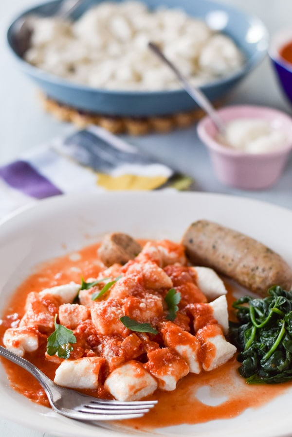 Ricotta gnocchi with red gravy, sausage and spinach  on a plate