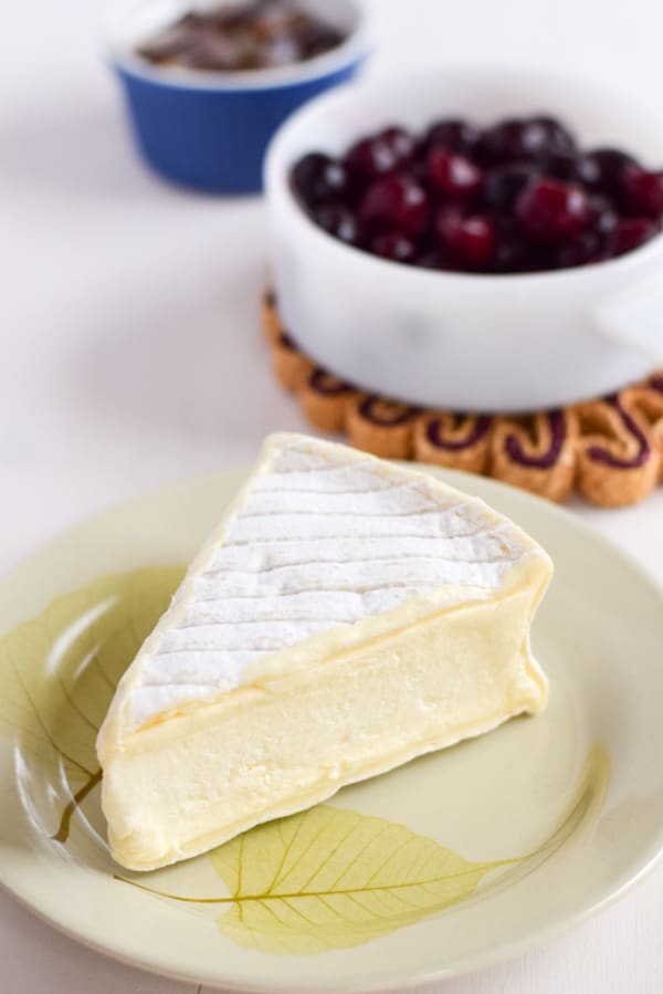 soft cheese on a plate and cherries in a bowl