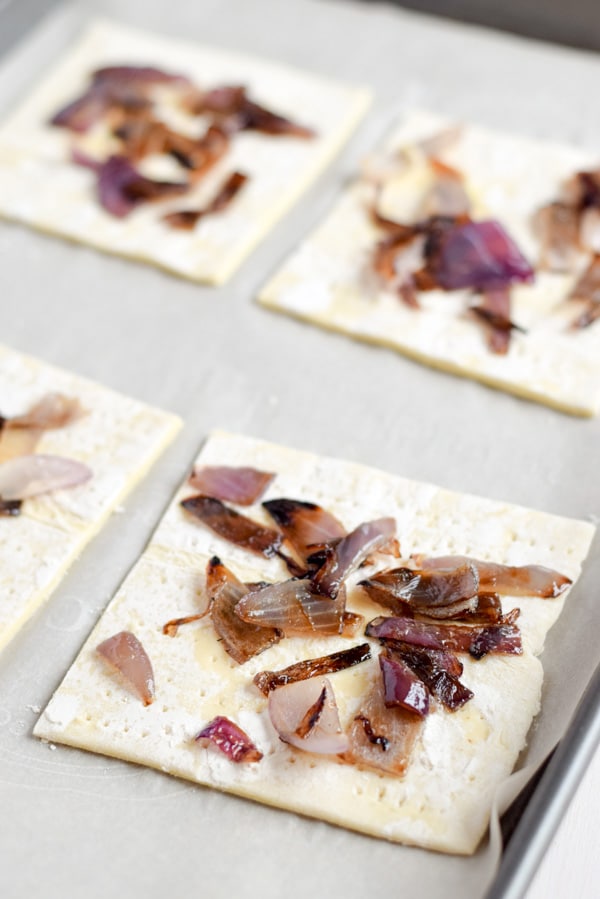 Onions on the puff pastry squares on a pan