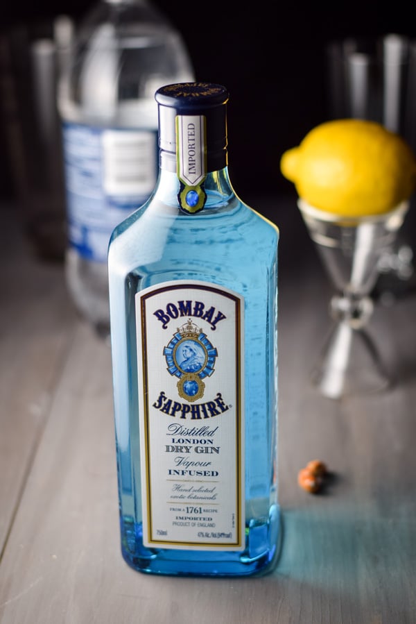 Gin, lemon and club soda on a table with a shaker and glassware