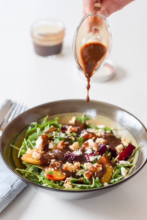 Drops of dressing dripping from the pourer onto the salad