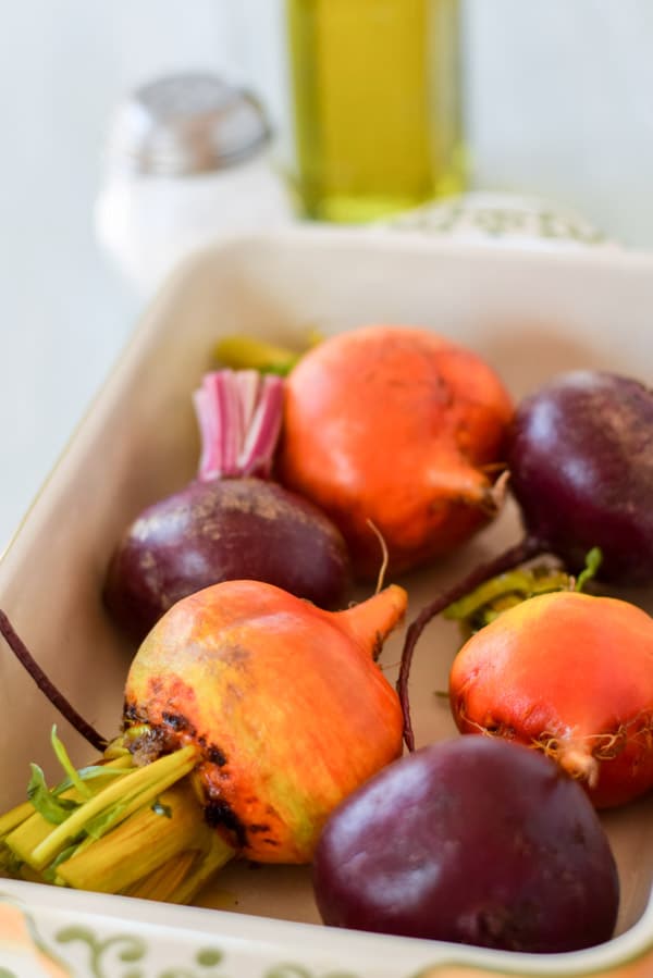 A baking dish with beets with the beet all cut and oil and salt in the background