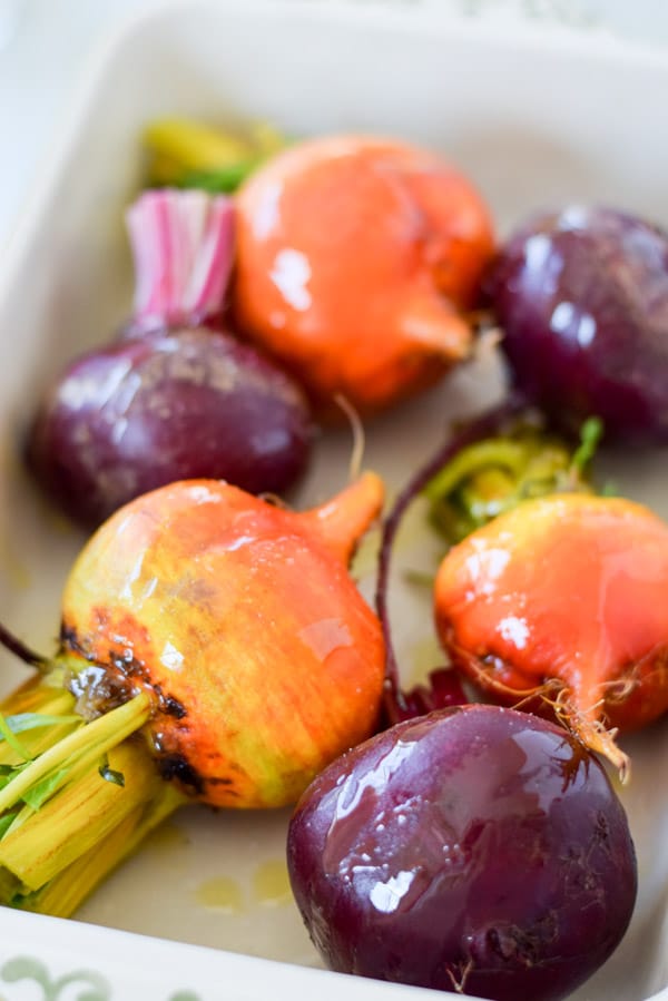 Close up of a baking dish with beets in it and oil poured on
