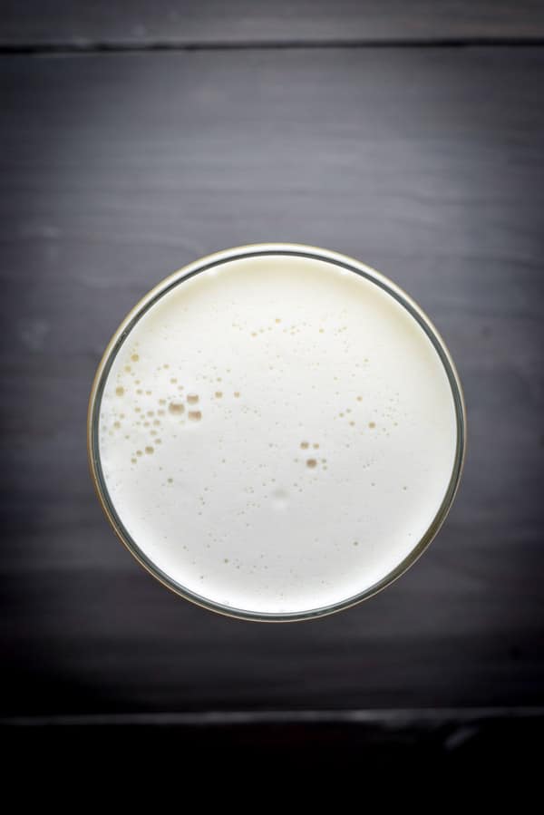 Overhead view of a foamy cocktail on a grey table