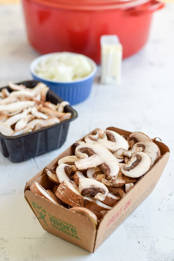 Sliced mushrooms in front of butter, flour and a red pan