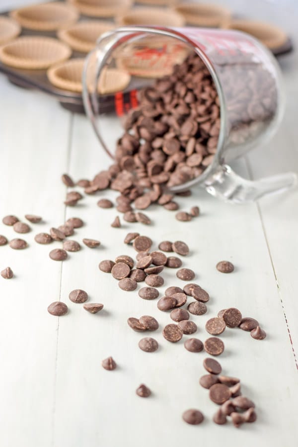 A glass measuring cup on its side with chocolate chips spilling out of it