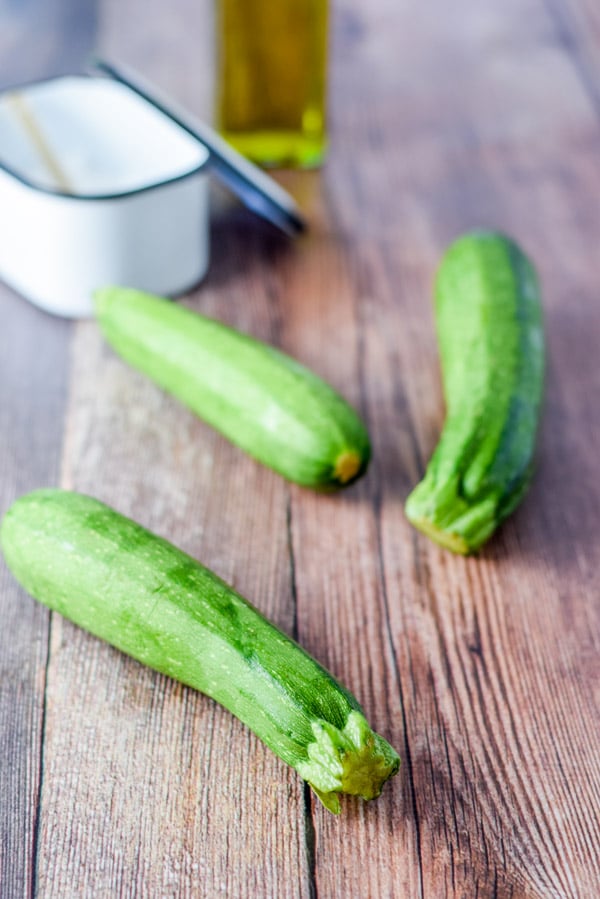 Zucchini, salt and oil on a wooden table