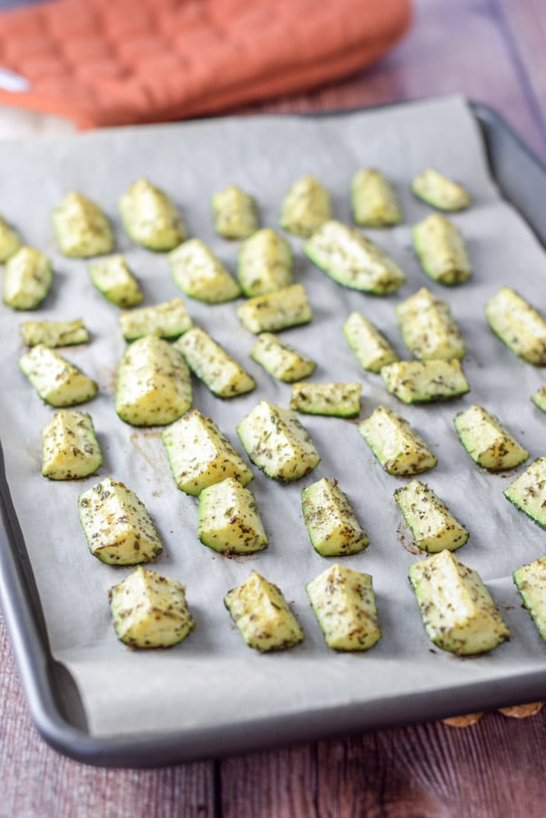 A jelly roll pan with herb zucchini on it straight out of the oven