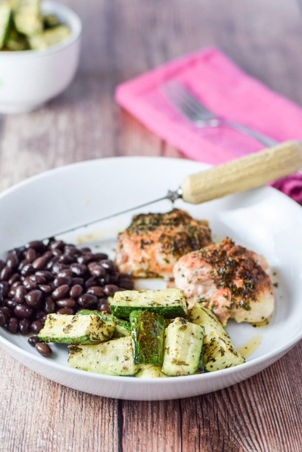 Zucchini, beans and chicken thighs on a deep dish with more zucchini in a bowl in the background