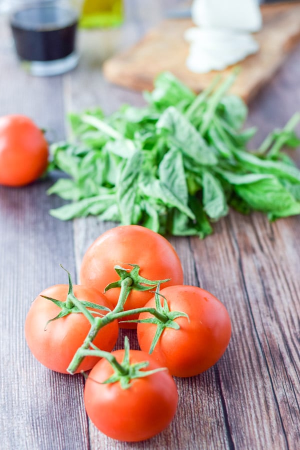 Tomatoes, basil, sliced cheese, vinegar and oil on a wooden table