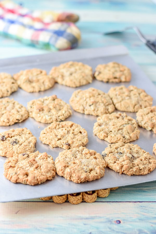 A cookie sheet with the cookies straight from the oven with an oven mitt and spatula in the background