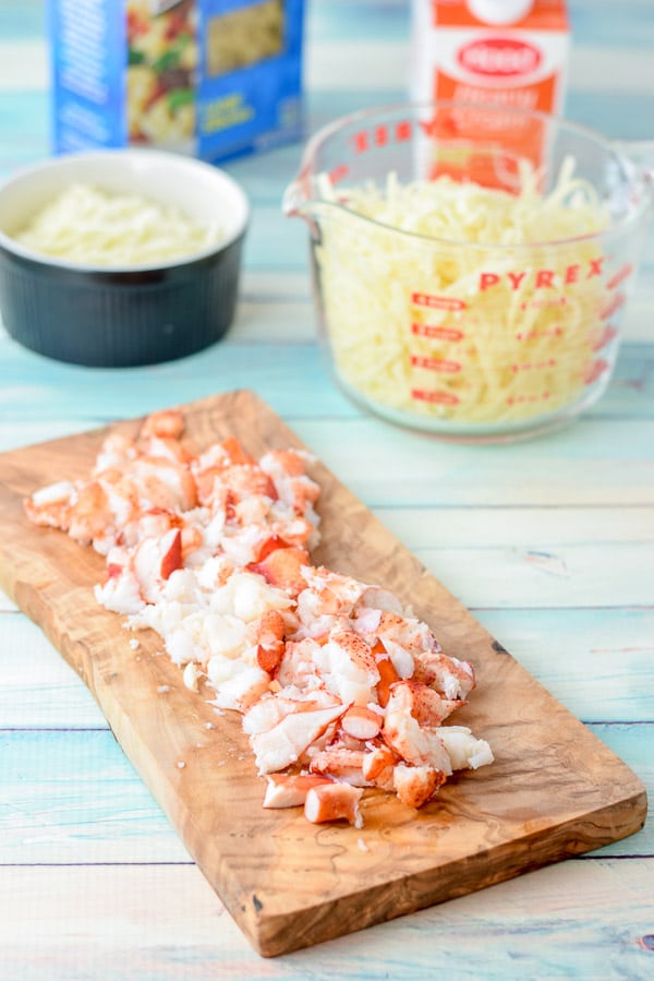 Lobster cut up on a board, with cheese, cream and elbow macaroni behind it