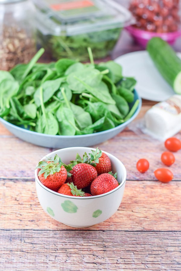 Strawberries, spinach, arugula, tomatoes, cucumber and pecans on the table