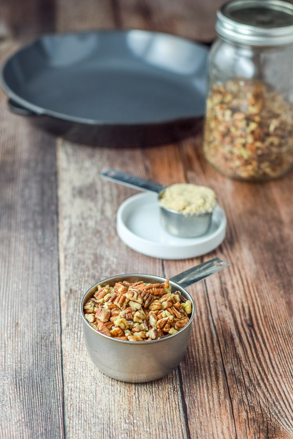 Pecans, brown sugar, a jar of pecans and a cast iron pan in the background