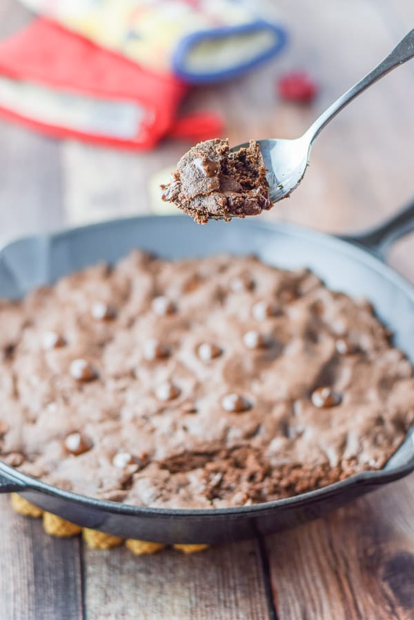 A spoonful of brownie held above the skillet