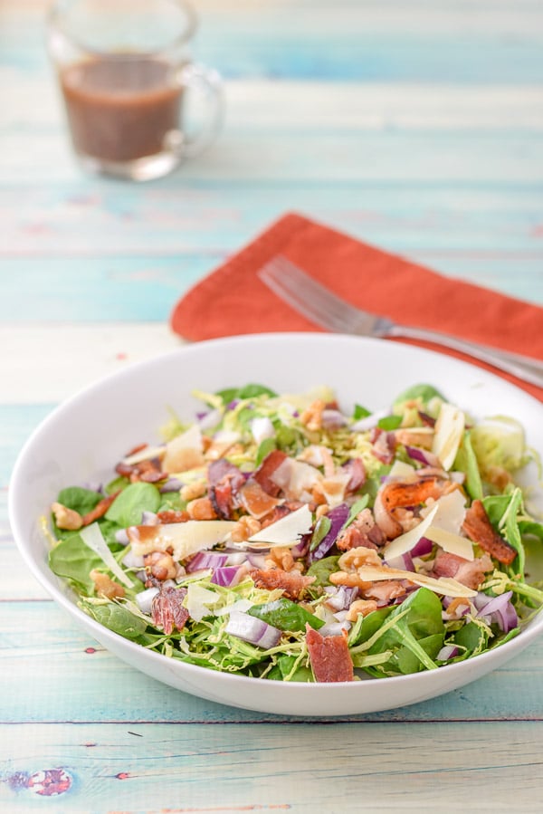 Dressing poured for the salad with a napkin, fork and dressing in the background