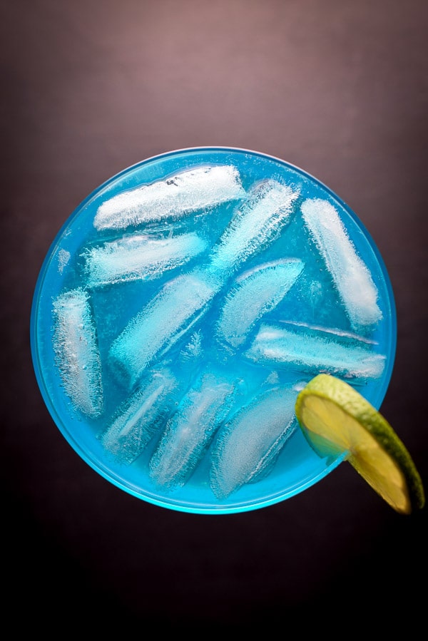 Overhead view of a round glass with a blue cocktail in it