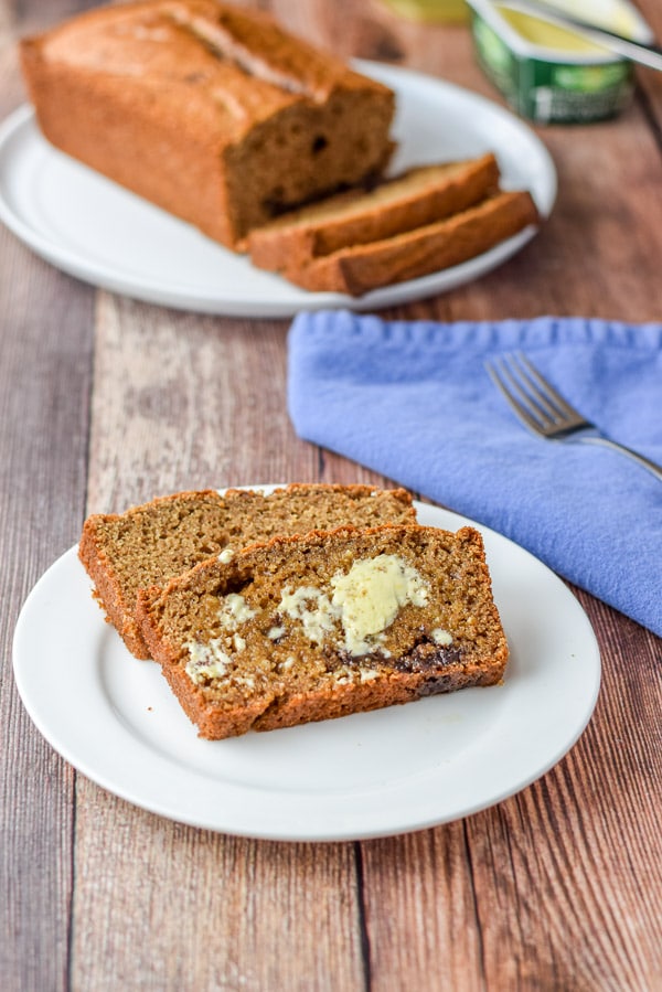 Butter on one of the pieces of bread on a plate with another piece