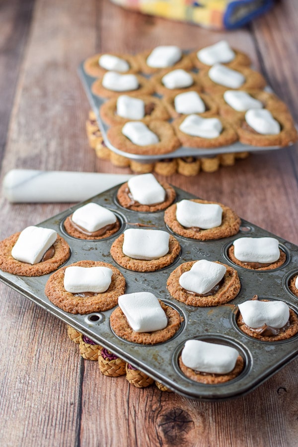 Marshmallows placed on top of the cookies in the muffin tins