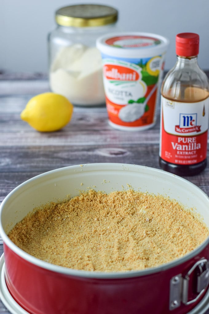 The bread processed and pressed down in the springform pan with vanilla, ricotta, lemon and sugar in the background