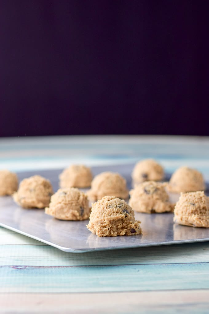 Cookie dough balls on a cookie sheet on a green table