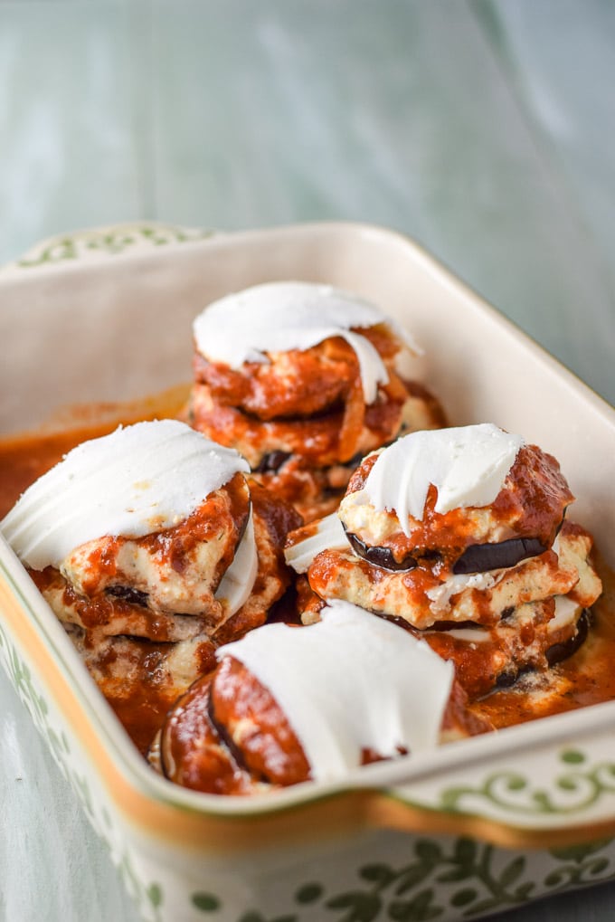 More layers of eggplant, gravy and cheese in a baking dish on a green table