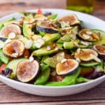 Oil and balsamic vinegar dribbled on the salad with the bottles still in the background - square