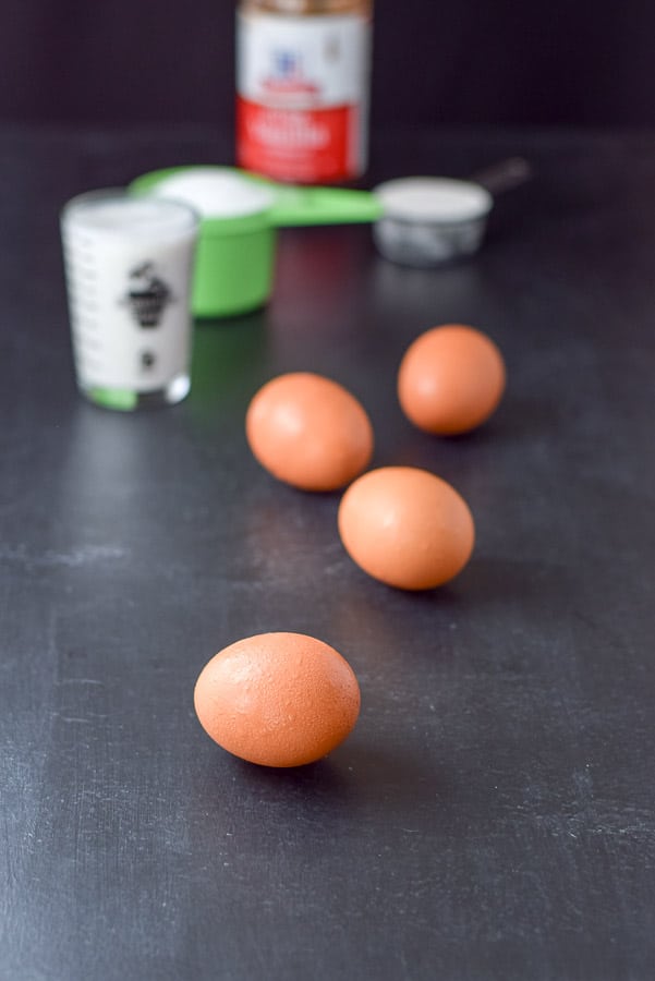 Eggs, almond milk, sugar, flour and vanilla on a black board