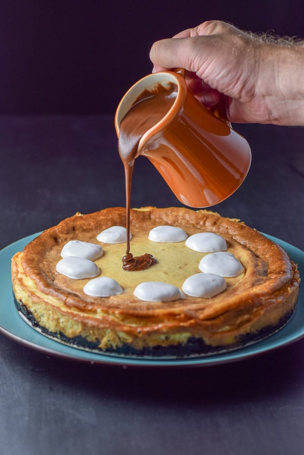 Fluff dolloped on and ganache made and being poured onto the cheesecake