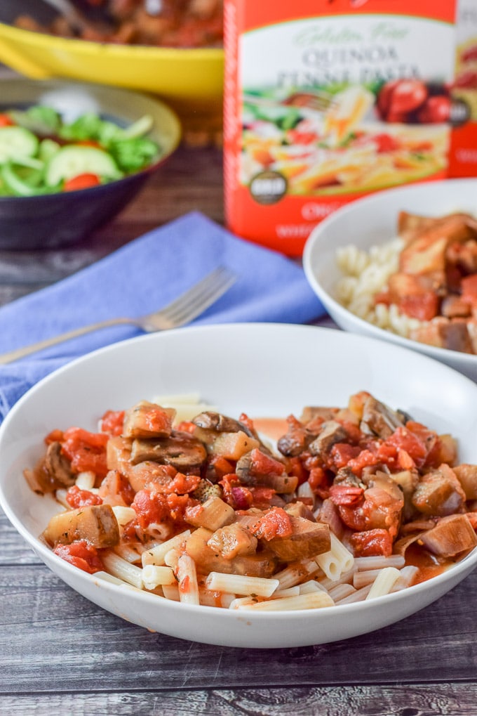 A close up of the pasta with the veggies on it with boxed pasta, a salad in the background