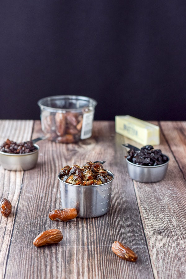 Dates, prunes, raisins and butter all measured out on a wooden table