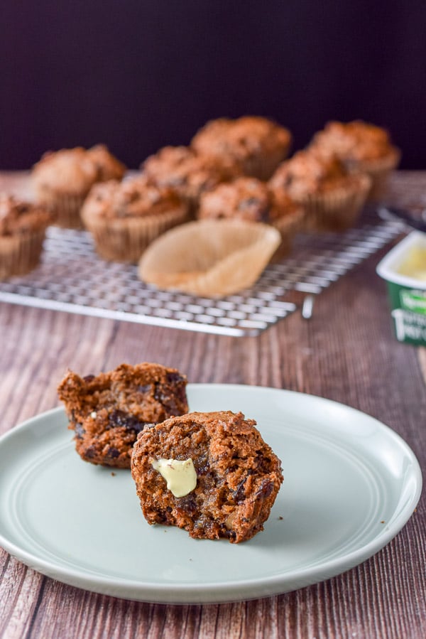 Butter melting on one of the muffins on a green plate with more muffins in the background