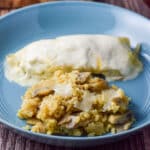 A deep blue dish with rice and cheese along with an enchilada - square