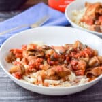 A deep white bowl filled with penne with veggies on it - square