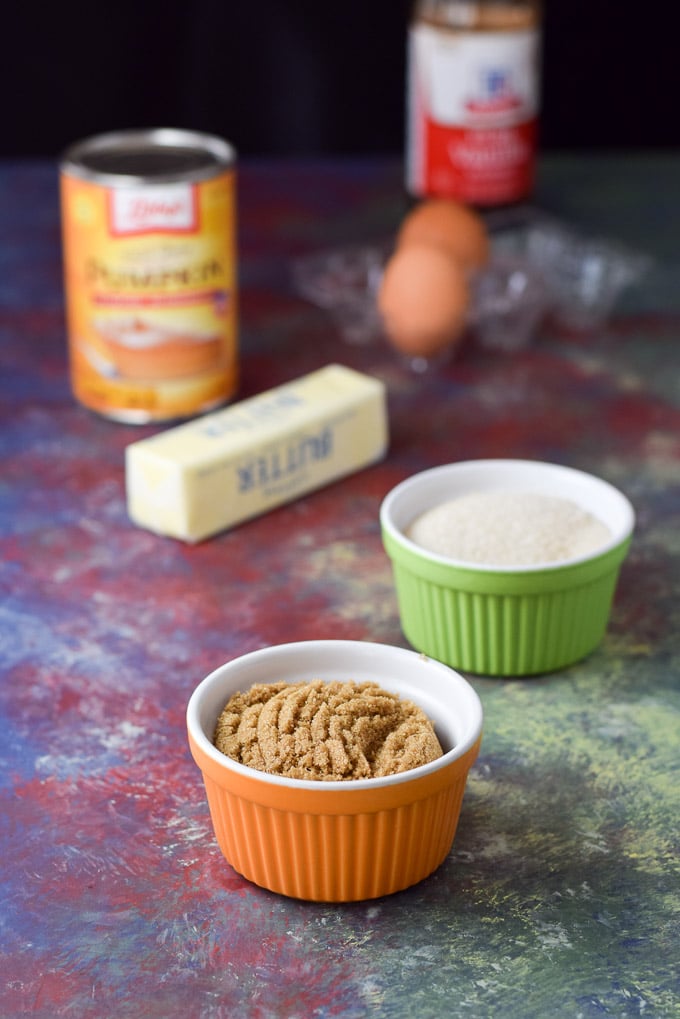 Brown sugar, cane sugar, butter, pumpkin, eggs and vanilla on a colorful board
