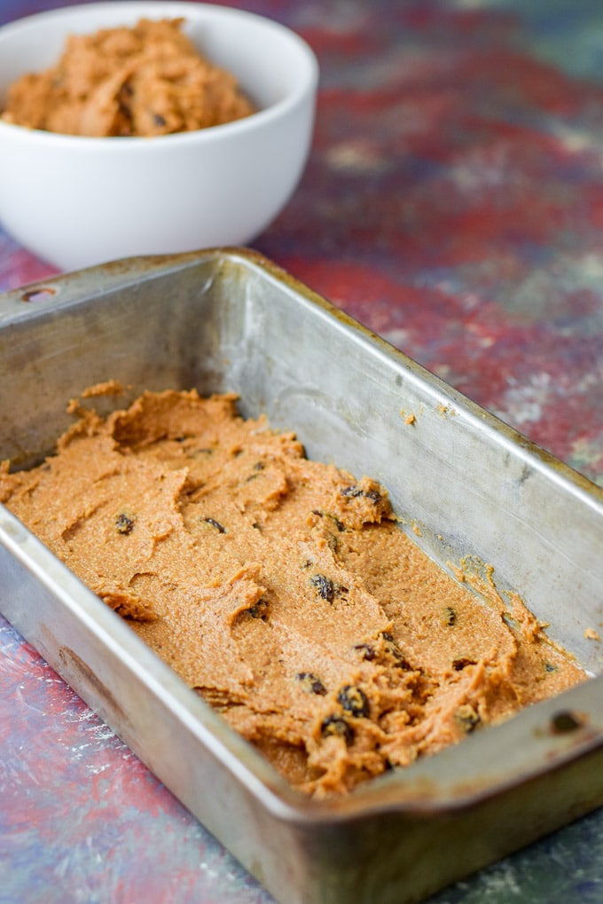 Pumpkin batter spread in a greased pan ready for the layering. There is batter in the background in a white bowl