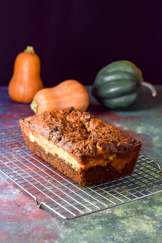 layered Pumpkin bread cooling on the wire rack. There are also whole squashes in the background