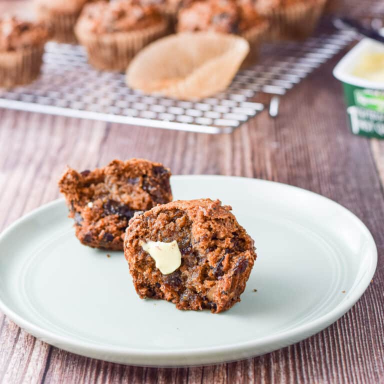 A plate with one of the date muffins cut and slathered with butter - square
