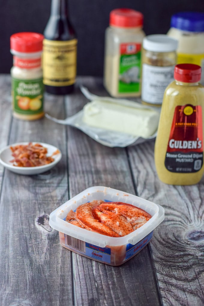 Lobster, cooked bacon, cream cheese and condiments like garlic powder, horseradish and mayo on a grey table