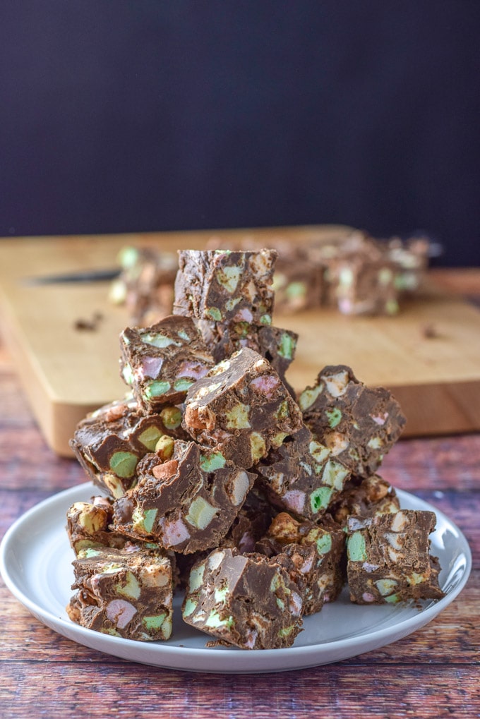 Fudge piled up on a plate with a chopping block of more fudge behind it