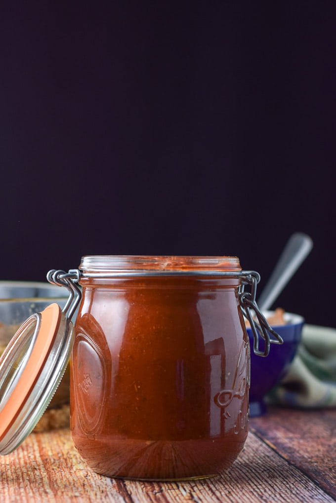 Vertical view of the red enchilada sauce with a bowl of refried beans in the background