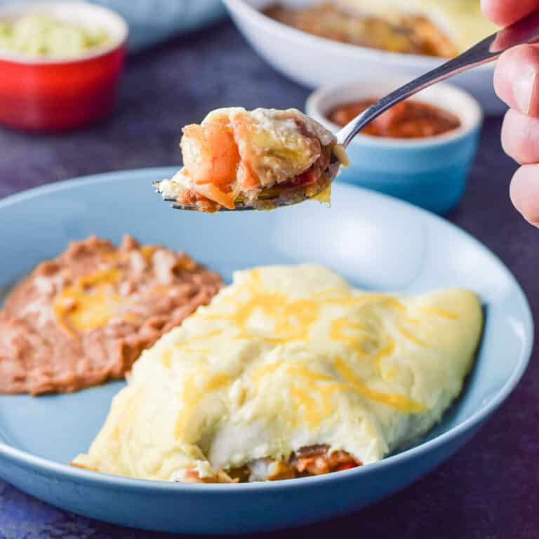 A forkful of shrimp enchiladas over the plate