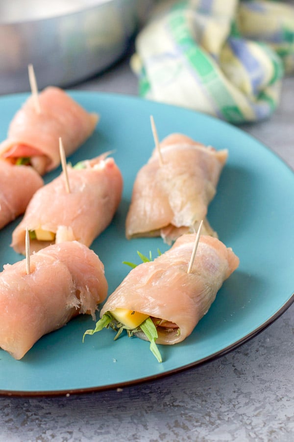 Chicken rolled up with toothpicks sticking out of them on a blue plate