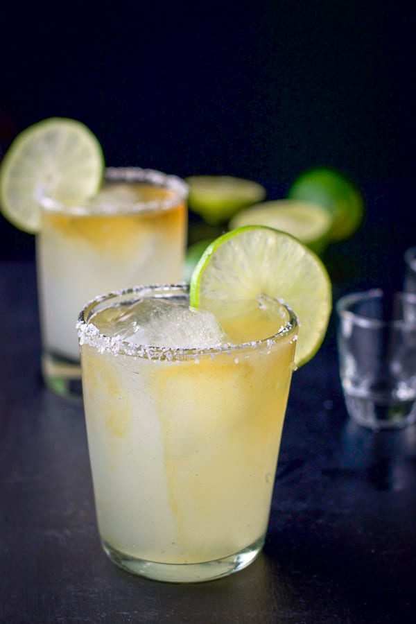 Grand Marnier poured in both margaritas with limes on the rims and in the background