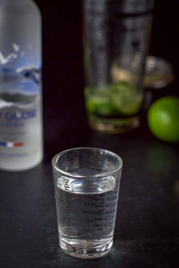 vodka poured out with the shaker in the background along with the bottle and lime