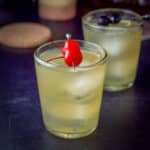 Two glasses of the whiskey sour, red cherries in front, dark in back - square