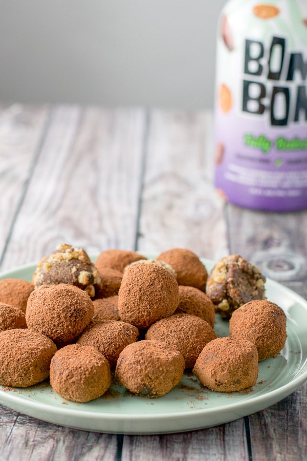 A green plate with the chocolate truffles rolled and dipped into cocao powder and some cookie crumbs