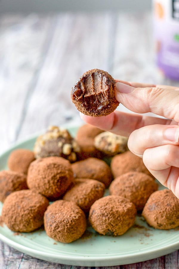A hand holding a truffle with a bite taken out of it, all gooey and delicious