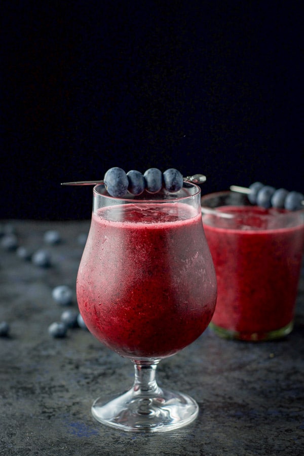 tulip glass and double old fashioned glass filled with the daiquiri with blueberries on the table